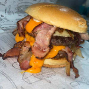 PÃO BRIOCHE,  MAIONESE,  2 CARNES ARTESANAL 180G,  QUEIJO MUSSARELA,  QUEIJO CHEDDAR CREMOSO,  CEBOLA CARAMELIZADA,  FATIAS DE BACON DEFUMADO. ACOMPANHA FRITAS.